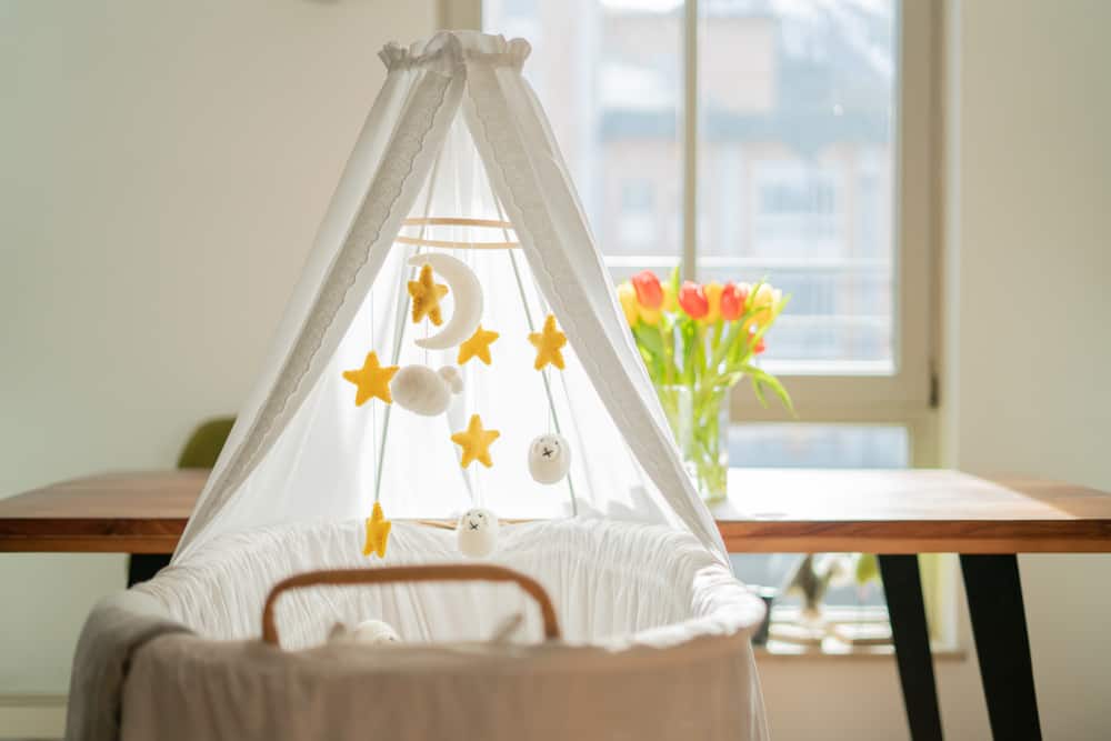 a baby bassinet with a canopy and mobile