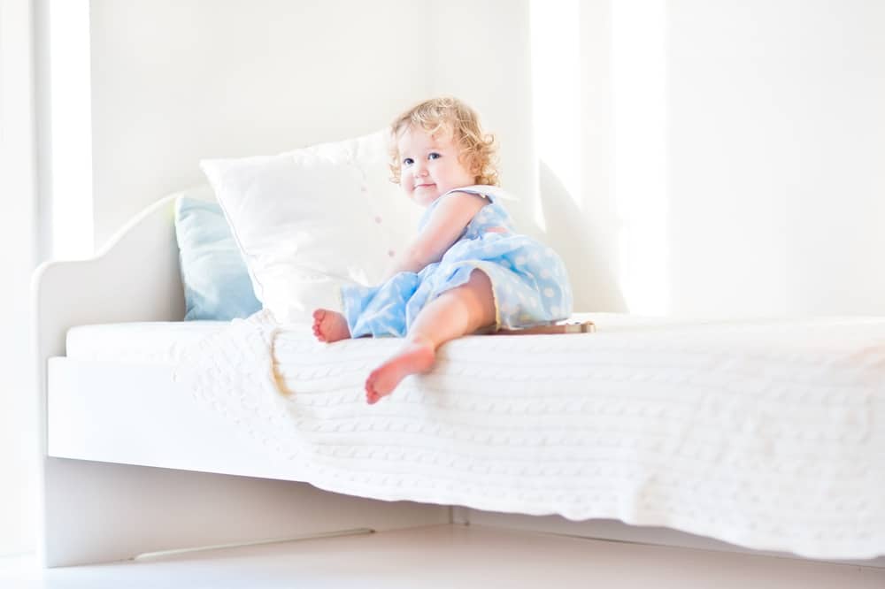 A girl sitting on her toddler bed