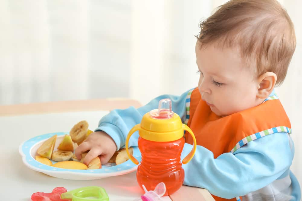 Baby eating in a high chair out of a bowl