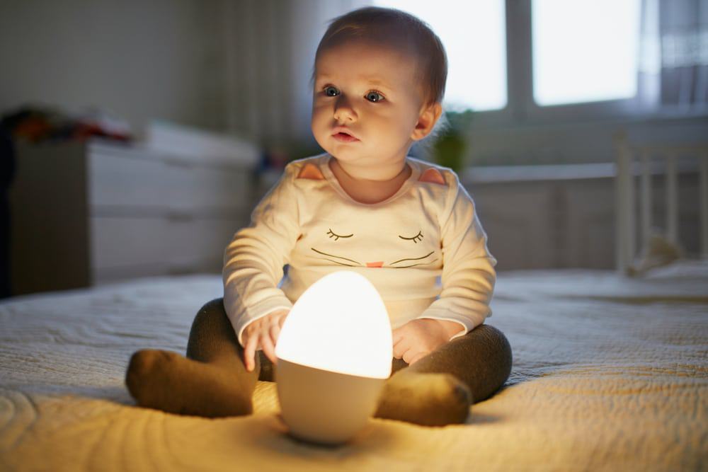 baby reading next to night light