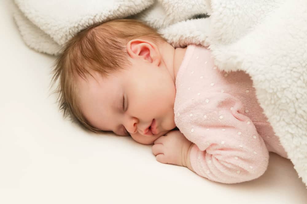 baby sleeping on stomach under a blanket