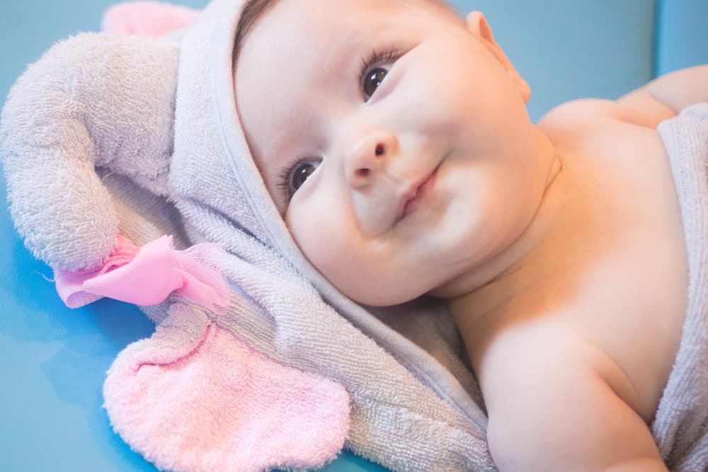 close up of smiling baby wrapped in a pink towel