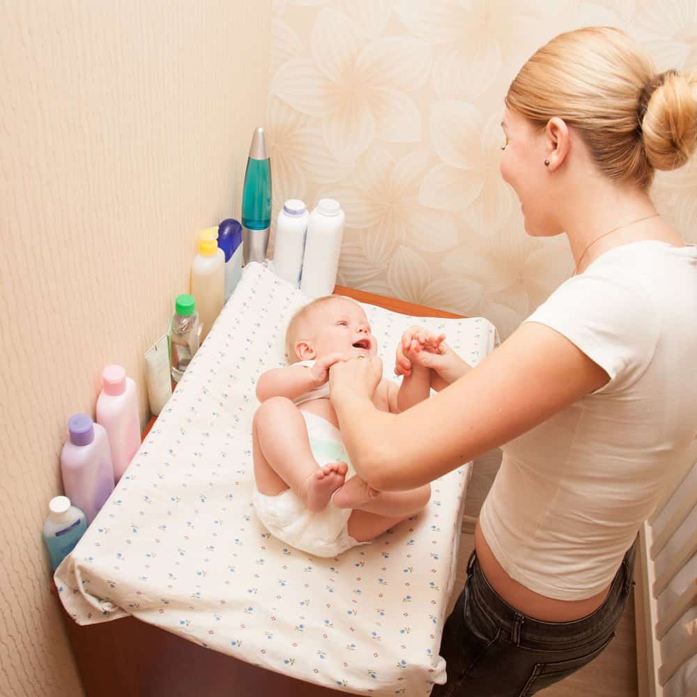 mom changing her baby’s diaper on a changing pad