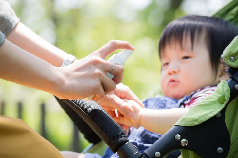 bug spray being sprayed on baby in stroller