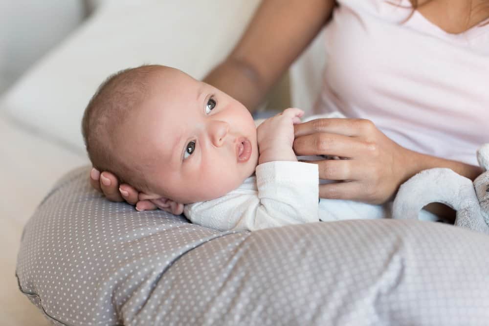 Close up shot of baby resting on a nursing pillow in his mother's lap