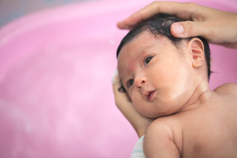 mom gives Asian baby with acne a bath