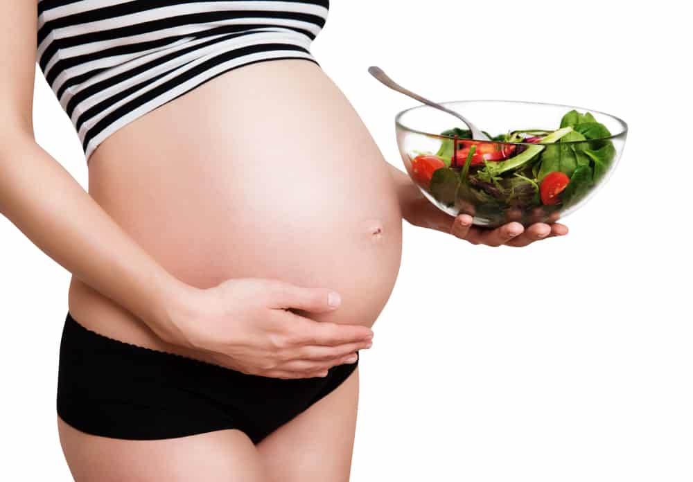 a woman holding onto a bowl of leafy greens