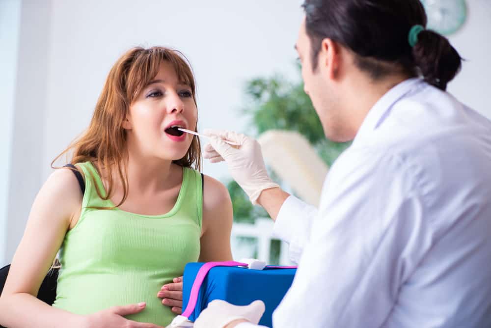 a pregnant woman having a throat swab taken by a doctor