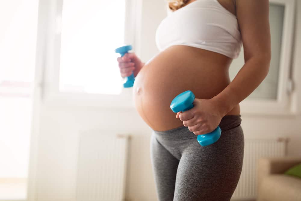 a pregnant woman with dumbbells