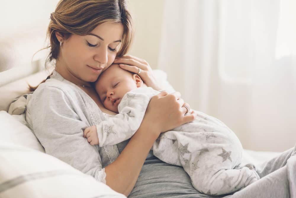 mom laying on a bed while holding newborn baby