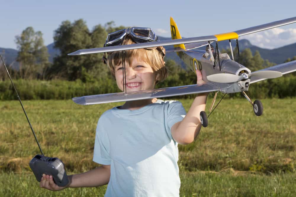 smiling child holding remote control airplane