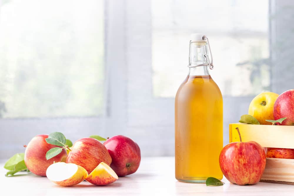 some apples and a bottle of apple cider vinegar