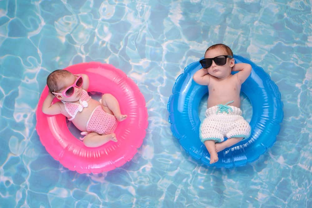 twin babies lounging in a pool with sunglasses on