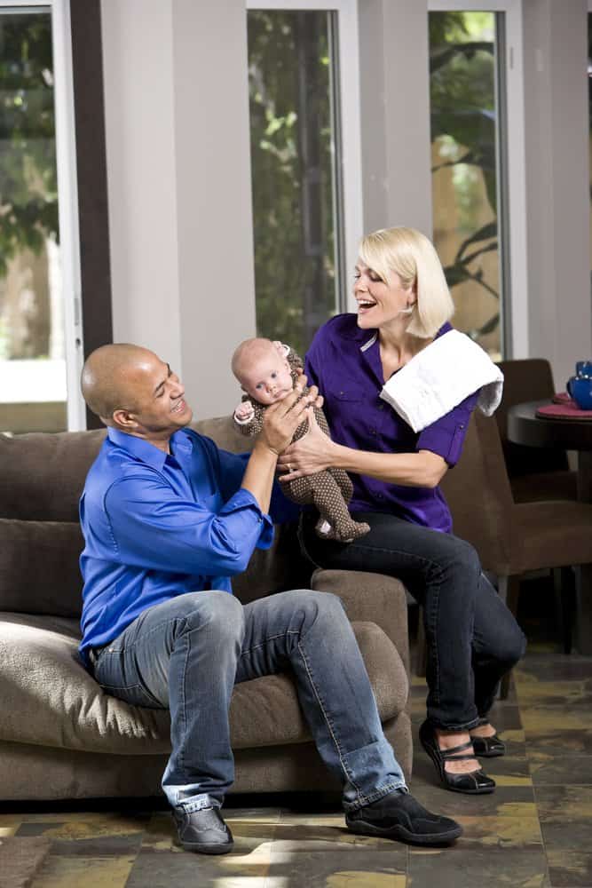 Two parents hanging a baby off that's wearing a burp cloth