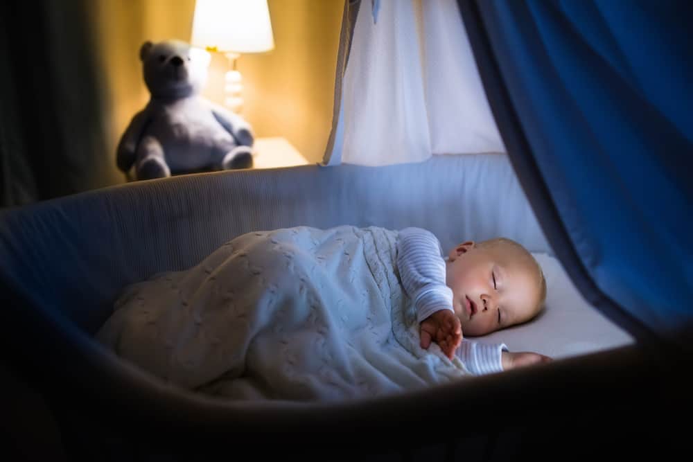 baby sleeping in a blue bassinet