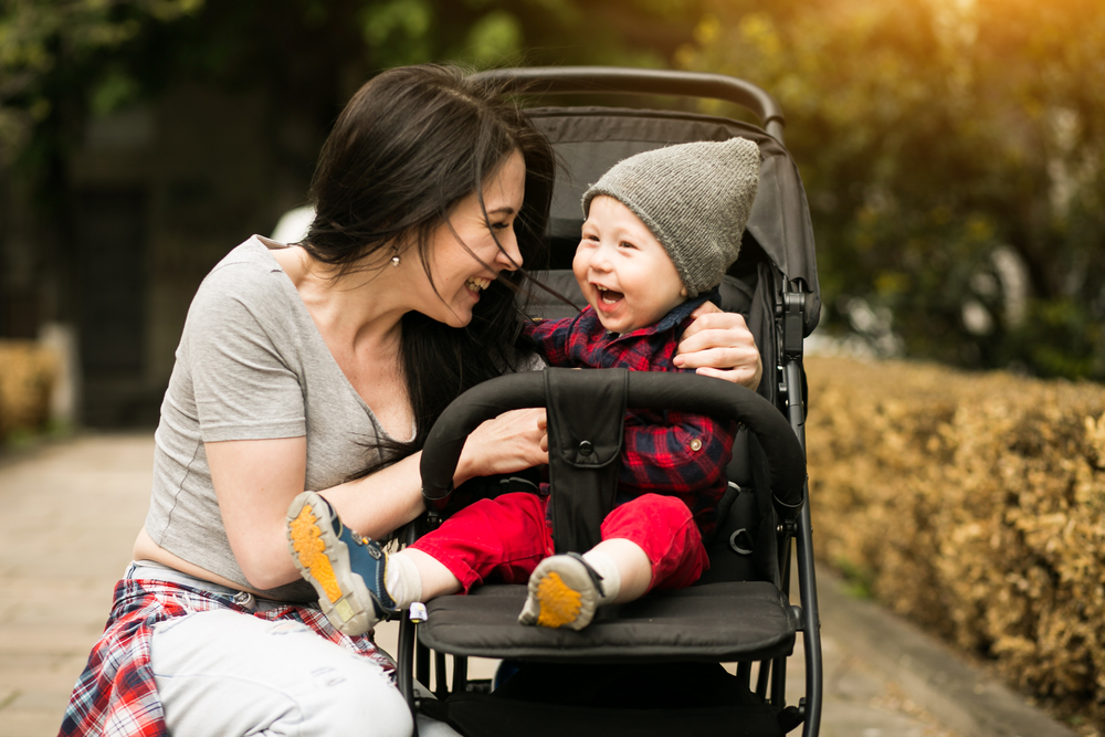 Woman kneeling and hugging baby in stroller