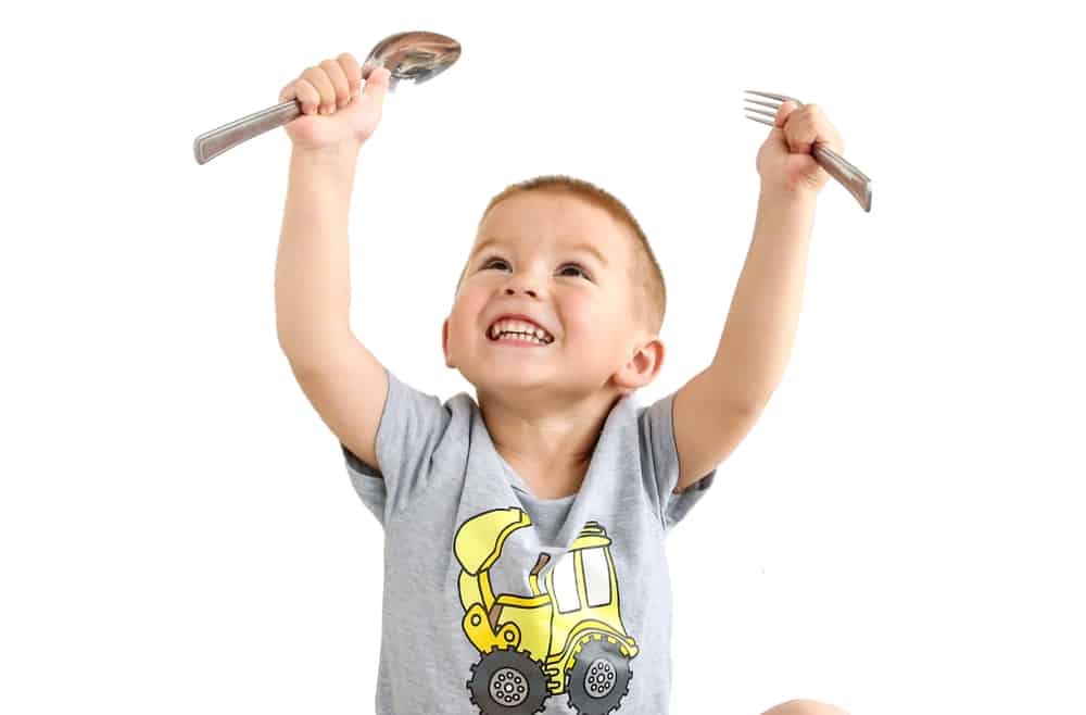 Young boy holding a fork and a spoon